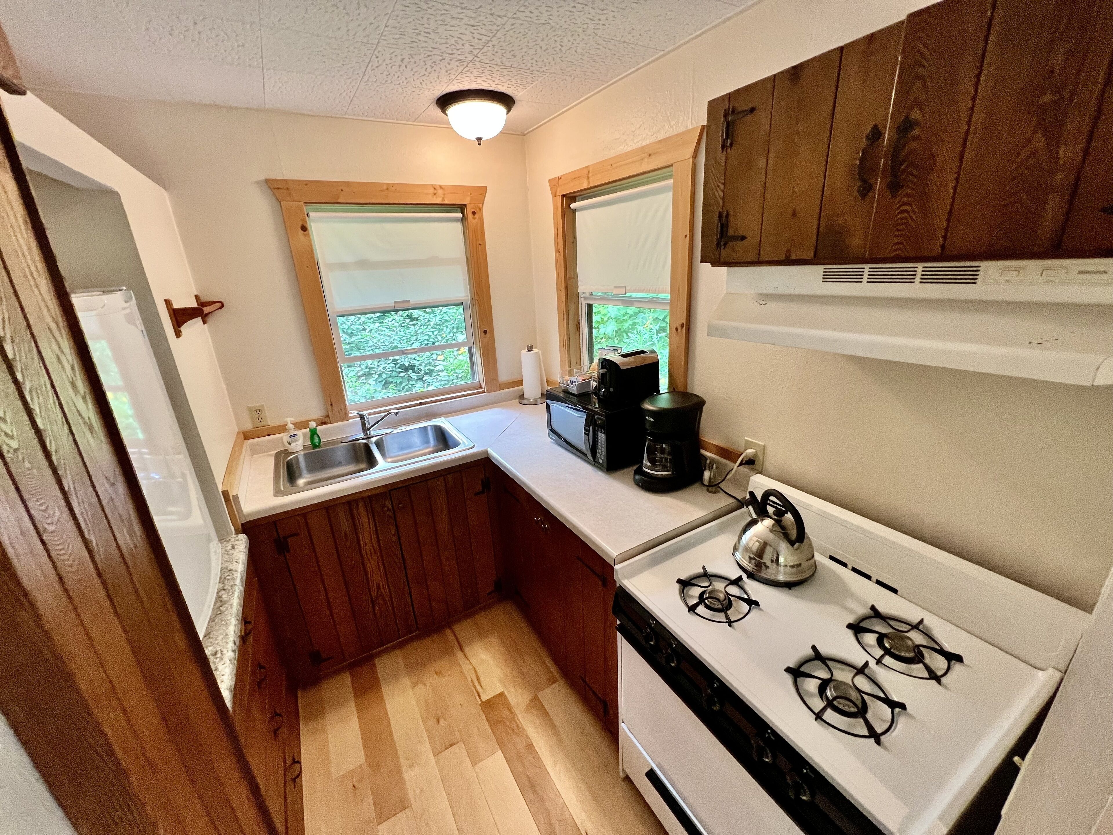A compact kitchen with wooden cabinets, a white stove, and a sink.