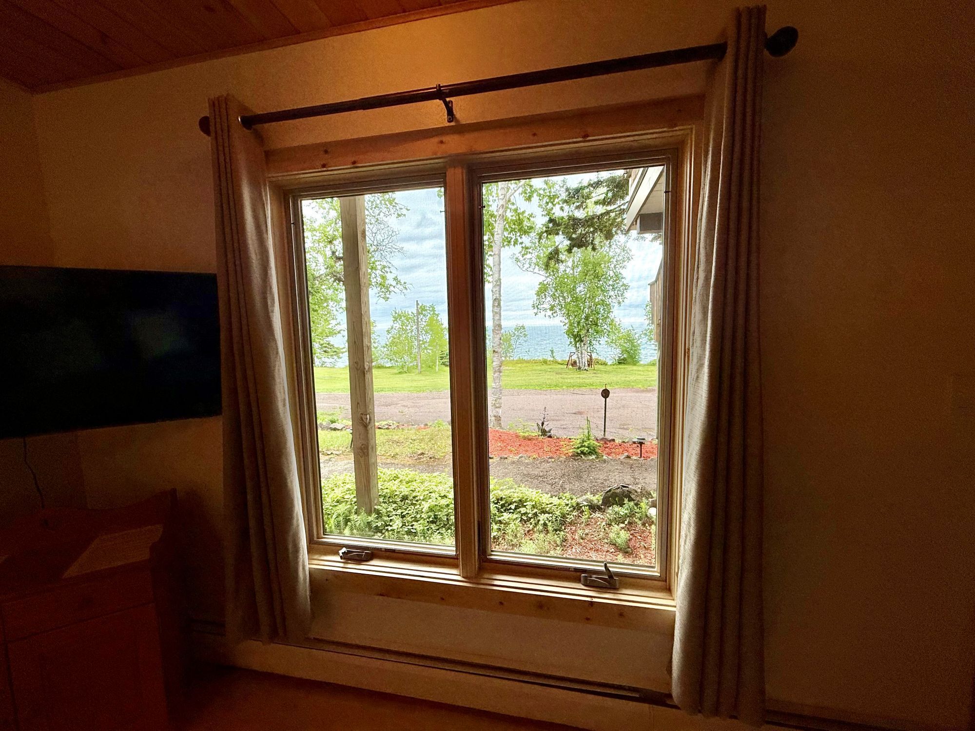 A room with a window overlooking a grassy area and a body of water.