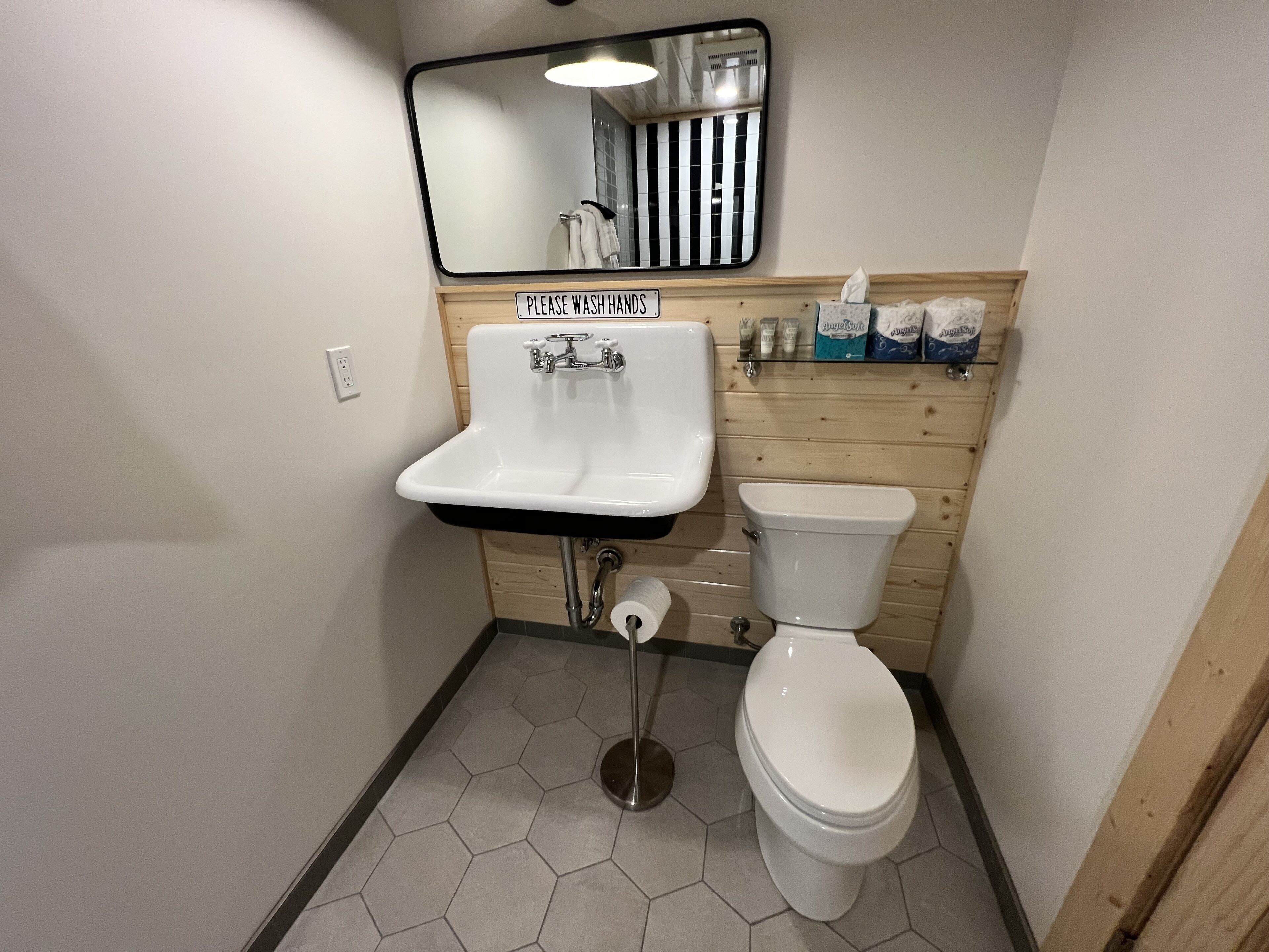 Een kleine badkamer met een wastafel, toilet en spiegel.