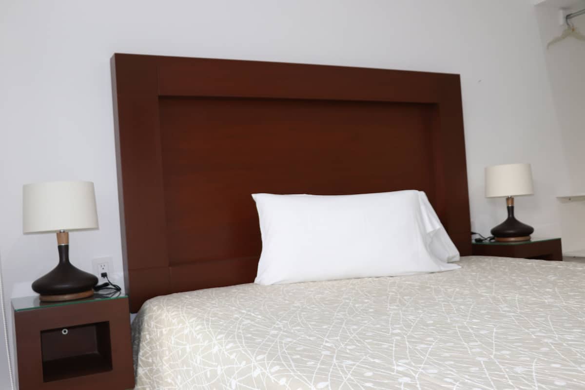 A hotel room with a large bed, two bedside tables with lamps, and a wooden headboard.