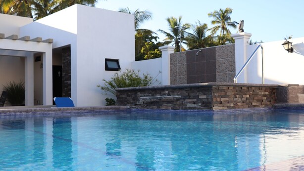 A swimming pool with a stone wall and a blue chair. - Mar Sol (Mazatlán)