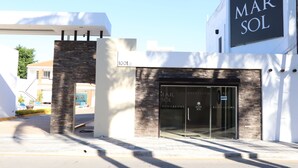 A modern building with a sign reading "BUNGALOWS MAR SOL" and a glass door entrance. - Mar Sol (Mazatlán)