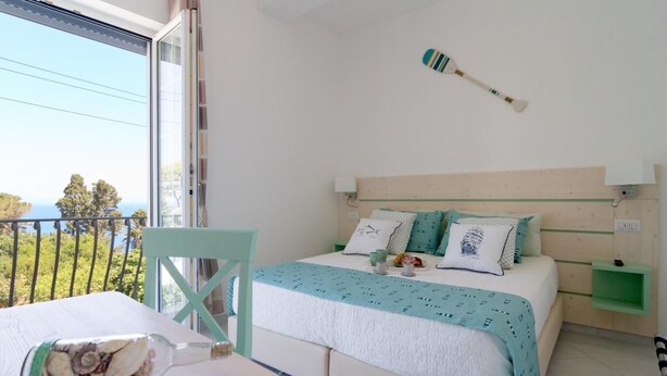 Un dormitorio con cama, mesita de noche, una silla y vistas al exterior.