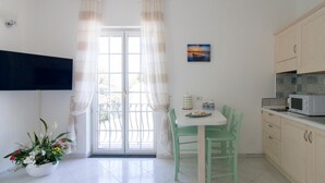 Una cocina con una mesa de comedor, sillas, un microondas y armarios.