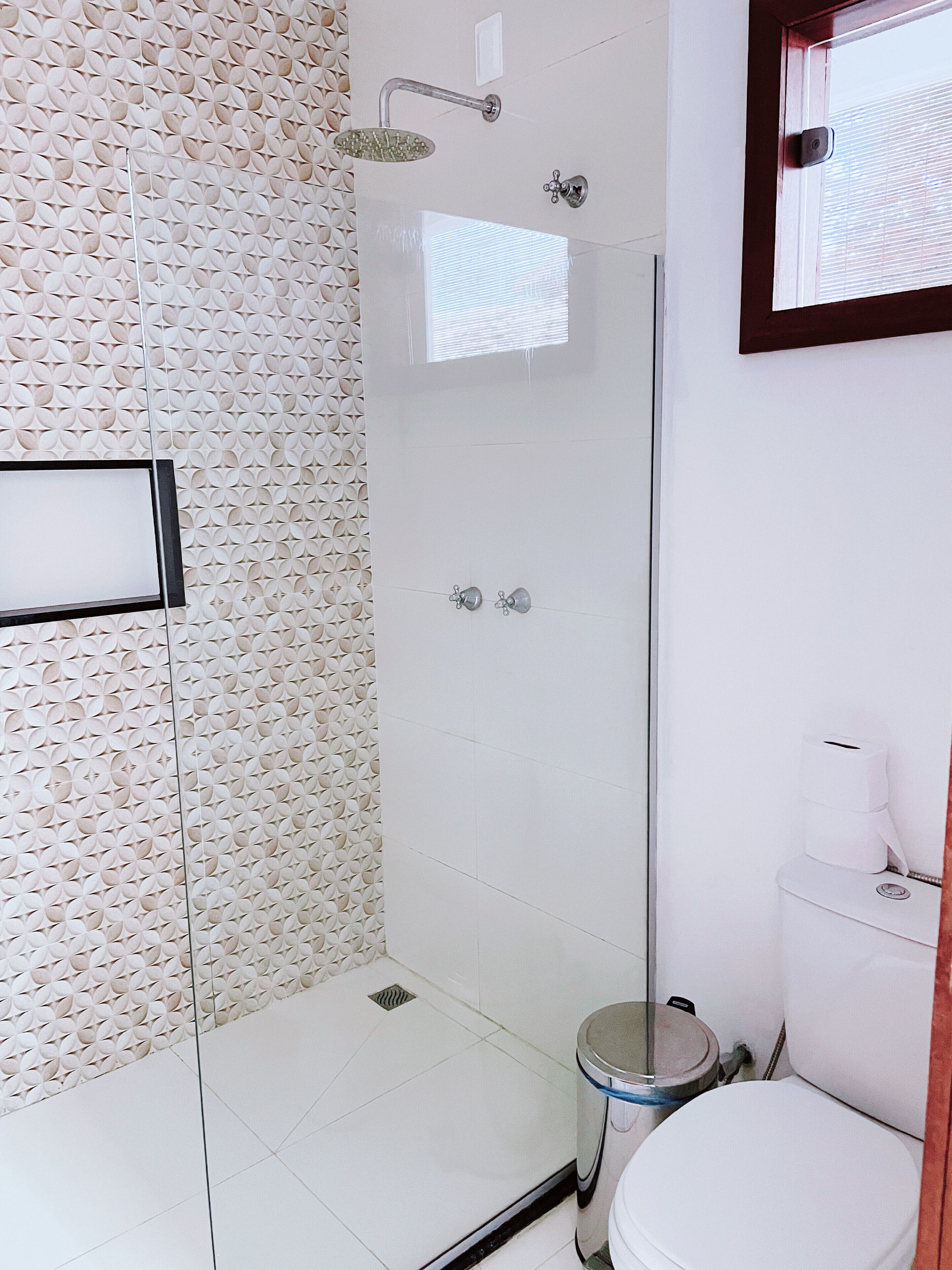 A bathroom with a shower, toilet, and a trash bin.