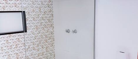 A bathroom with a shower, toilet, and a trash bin.