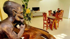 Un comedor con una mesa de madera, sillas y una estatua.