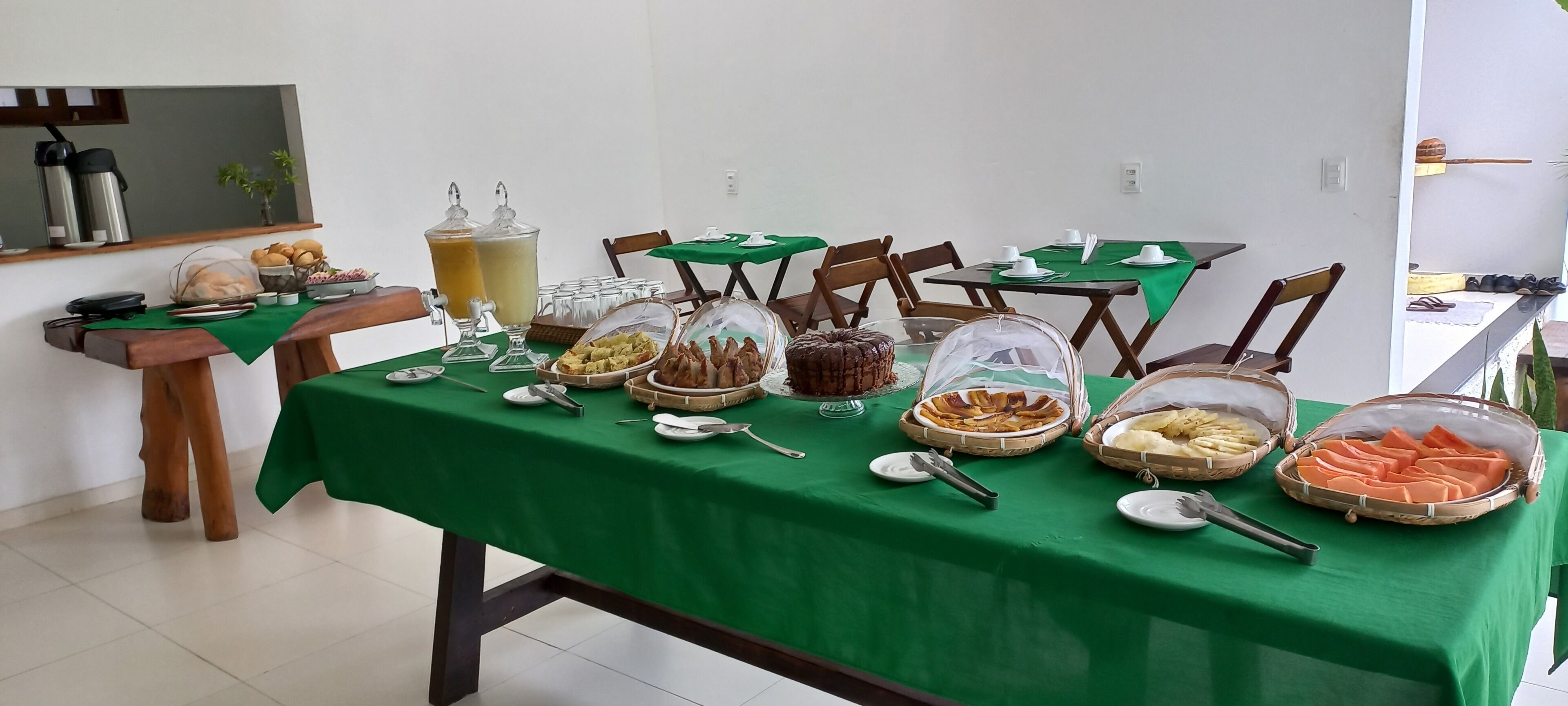 Zona pranzo con tovaglia verde, diversi cibi e angolo caffè.