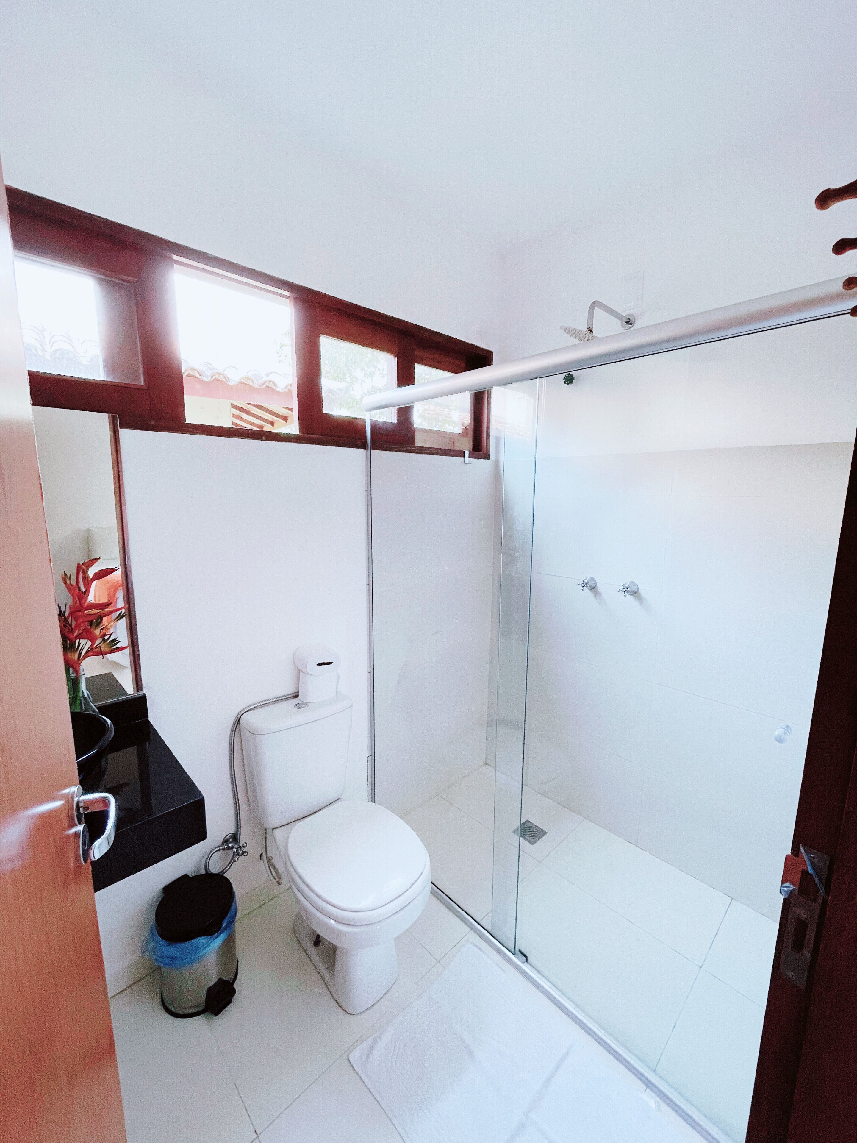 Ein modernes Badezimmer mit Toilette, Waschbecken und Duschkabine aus Glas.