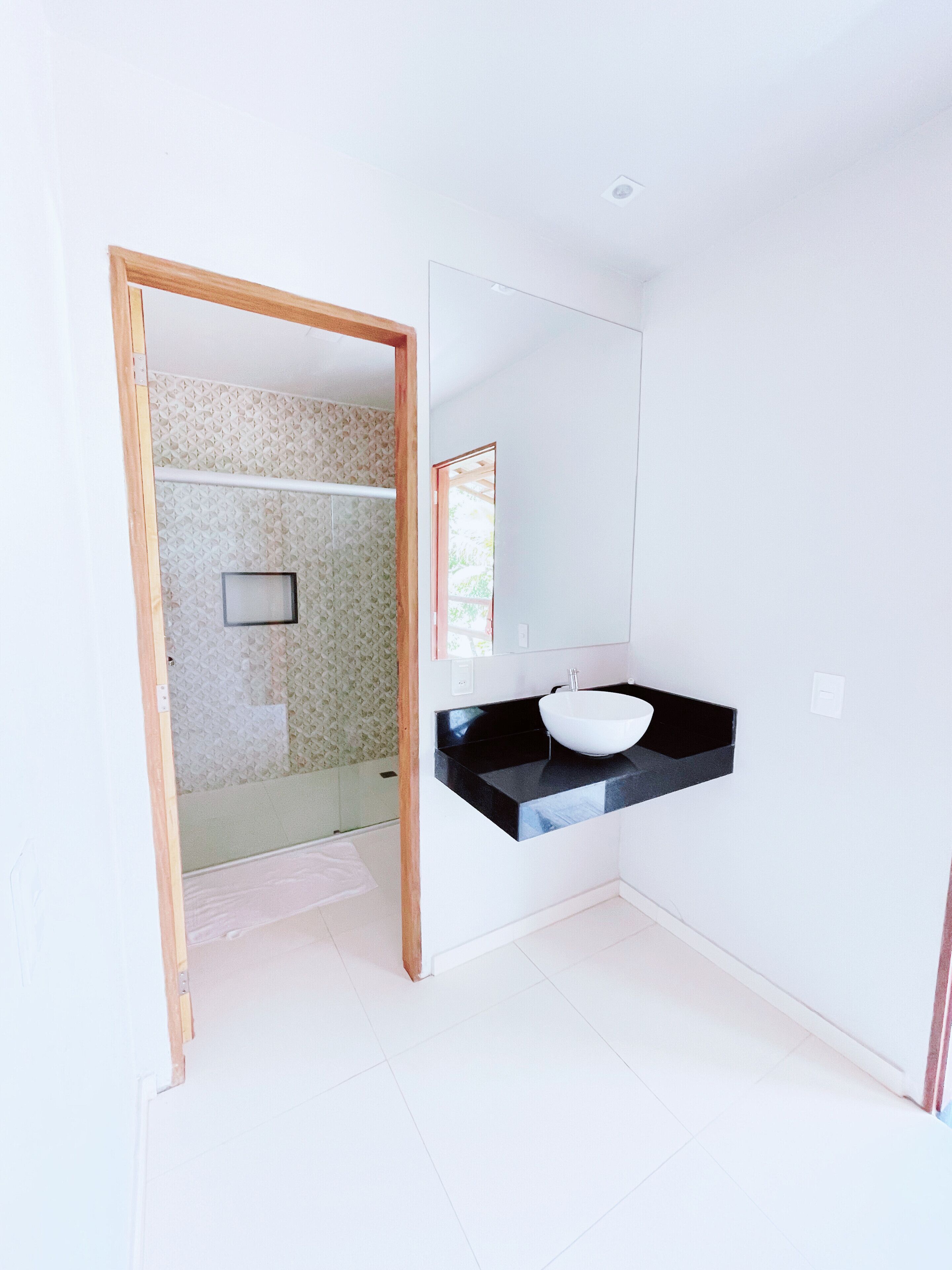 A modern bathroom with a black countertop and a white sink.