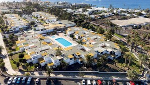 A coastal residential area with a swimming pool, white buildings, and palm trees. - Home2Book Modern Studio & Pool Costa del Silencio (Arona)