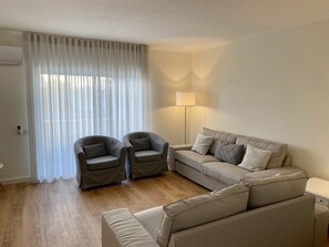 Relax in this inviting living room with a large sofa, two armchairs, and a floor lamp.
