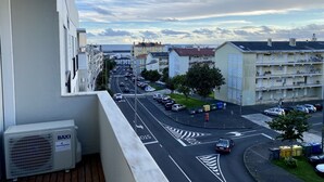 A balcony overlooking a street with parked cars and buildings.