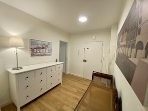 Comfortable hallway with a dresser, lamp, and artwork.