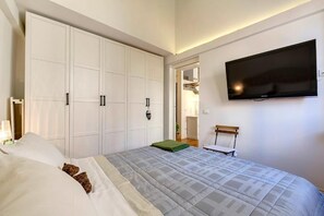 Ein Schlafzimmer mit einem Bett, einem an der Wand montierten Fernseher und einem Kleiderschrank.