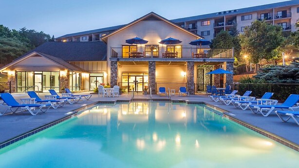 Un hotel con piscina, sillas de descanso y mobiliario exterior.