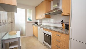 Uma cozinha moderna com armários de madeira, máquina de lavar louça, forno e frigorífico.