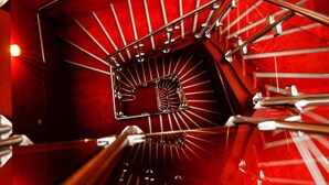 Un escalier en colimaçon avec une moquette rouge et des rampes en métal.