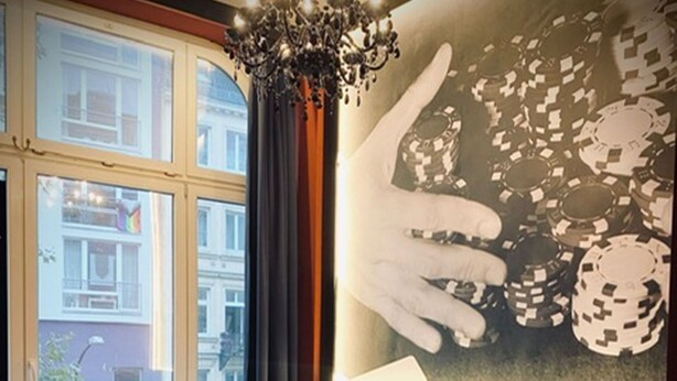 Une chambre d’hôtel avec deux lits, un lustre et une grande fenêtre donnant sur des immeubles.