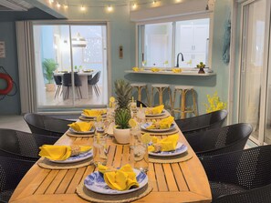 A dining area with a wooden table set for six, featuring yellow napkins, plates, and glasses.
