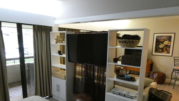 Una camera d'albergo con un letto, una televisione, un armadio bianco, un tavolino e una sedia.