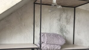 Ein Zimmer mit Betondecke und -wänden, ausgestattet mit einem Metallbettgestell und einer hängenden Leuchte.