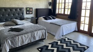 Un dormitorio con dos camas, una mesita pequeña y un ventanal con cortinas.