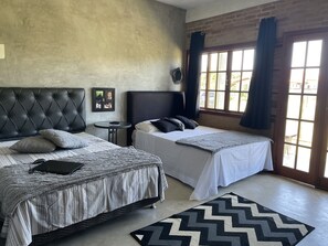 Une chambre avec deux lits, une petite table et une grande fenêtre avec des rideaux.