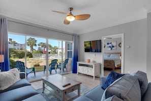 Relax in this spacious living room with a sofa, flat-screen TV, and sliding glass door leading to a patio with a neighborhood view.