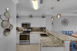 Enjoy cooking in this well-equipped kitchen with a stainless steel range, oven, and granite countertop.