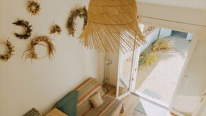 Una habitació amb un sofà, una taula petita i una cadira. Hi ha diverses decoracions a la paret i una finestra gran amb vista a l'exterior.
