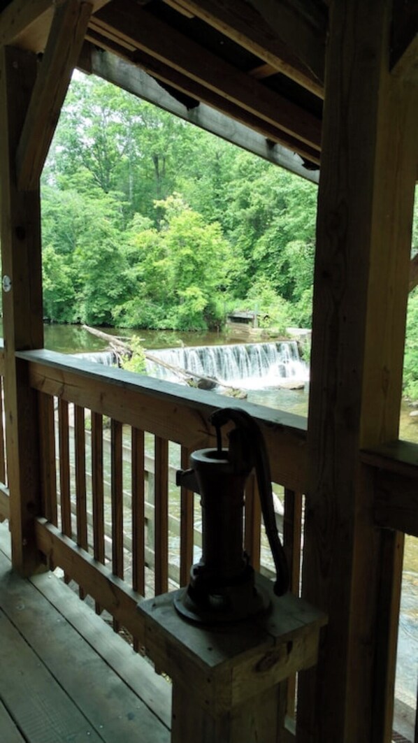 A wooden deck with a view of a waterfall and lush greenery.