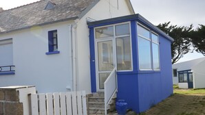 Un edificio blanco con puerta y ventanas azules, una escalera de piedra y una cerca blanca.
