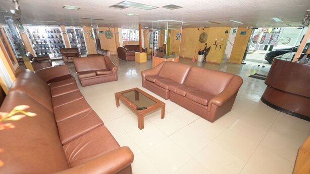 A spacious lobby with leather sofas, a coffee table, and a shoe display. - Hotel Aristi Chiclayo (Chiclayo)