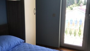 Een slaapkamer met twee bedden, een kledingkast en een schuifdeur naar een buitenruimte.