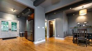 A spacious kitchen with wooden flooring, a refrigerator, and a dining area with a table and chairs. - Modern home in historic neighborhood with lower level game room by Loras College (Dubuque)
