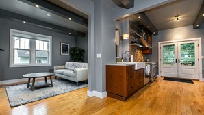 A modern kitchen with wooden flooring, a built-in oven, and a stone backsplash. - Modern home in historic neighborhood with lower level game room by Loras College (Dubuque)