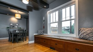 A modern kitchen with a dining area, wooden flooring, a built-in bench with storage, and a large window providing a view. - Modern home in historic neighborhood with lower level game room by Loras College (Dubuque)