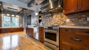 A modern kitchen with wooden cabinets, a brick backsplash, stainless steel appliances, and a large window providing natural light. - Modern home in historic neighborhood with lower level game room by Loras College (Dubuque)