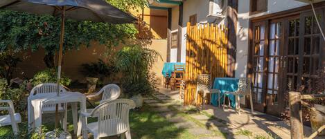 An outdoor patio with white plastic chairs, a table, and a large umbrella.