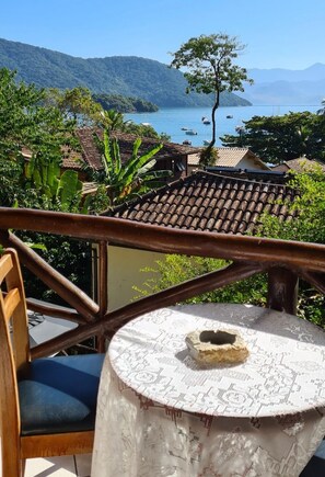A terrace with a view of a coastal landscape, including boats on the water and a mountainous backdrop. - Pousada Aquarela do Mar (Angra dos Reis)