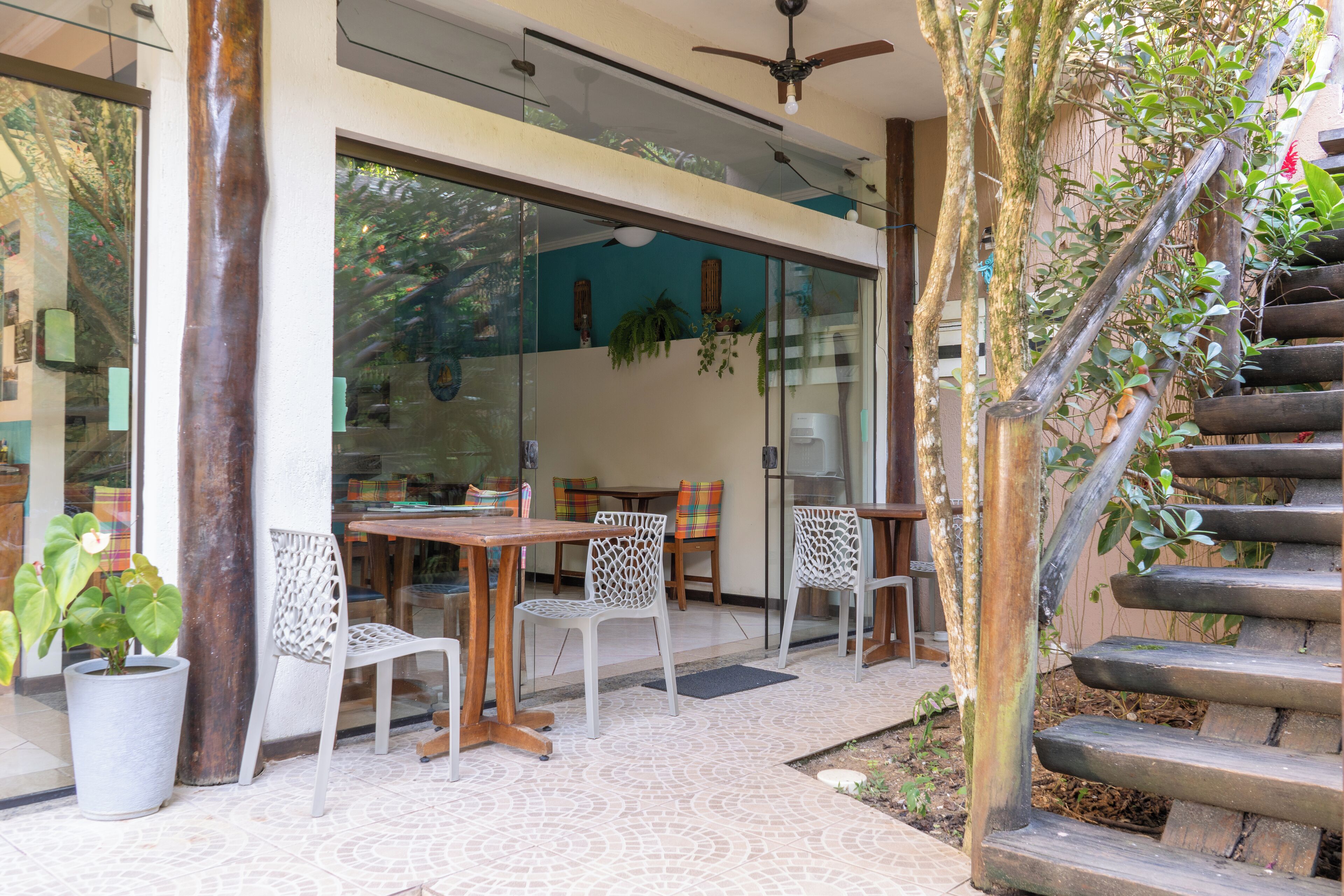 An outdoor patio area with a wooden table and chairs, a potted plant, and a staircase.