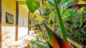 A tropical garden with a variety of plants, a decorative bird of paradise flower, and a small pond with pebbles and a statue. - Pousada Aquarela do Mar (Angra dos Reis)