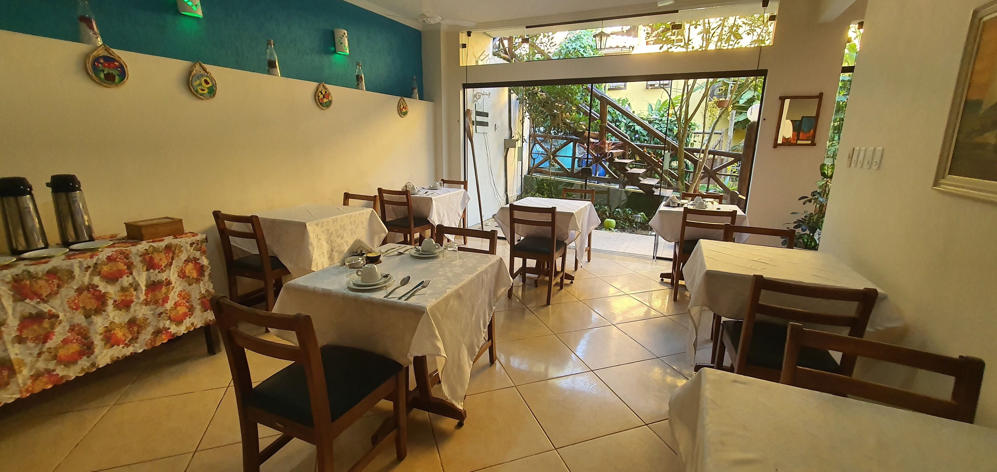 A restaurant with multiple tables and chairs, a staircase leading outside, and decorative wall art.