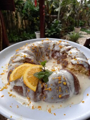 A bundt cake with orange slices and zest on a white plate. - Pousada Aquarela do Mar (Angra dos Reis)