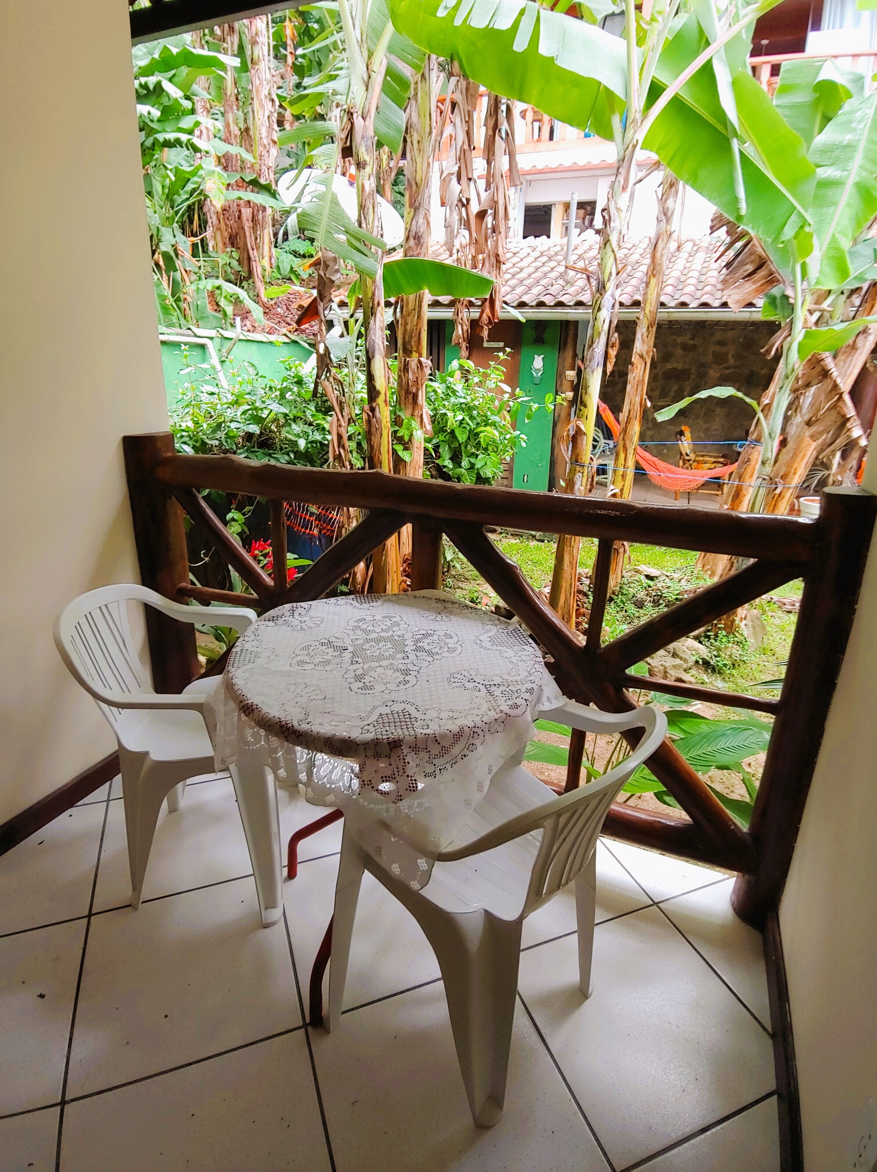 A small outdoor patio with a round table and two chairs, surrounded by a wooden railing.