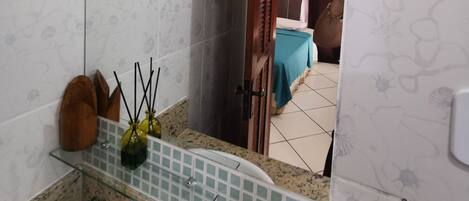 Un baño con lavamanos, espejo y zona de ducha.