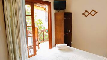 A bedroom with a bed, an air conditioning unit, a ceiling fan, a television, and a wooden cabinet.