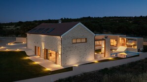 Una casa moderna con fachada de piedra, techo inclinado y una escalera visible que conduce a un nivel superior.