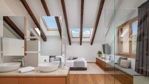 Un baño moderno con tragaluz, un espejo grande, lavamanos doble y cabina de ducha de vidrio.